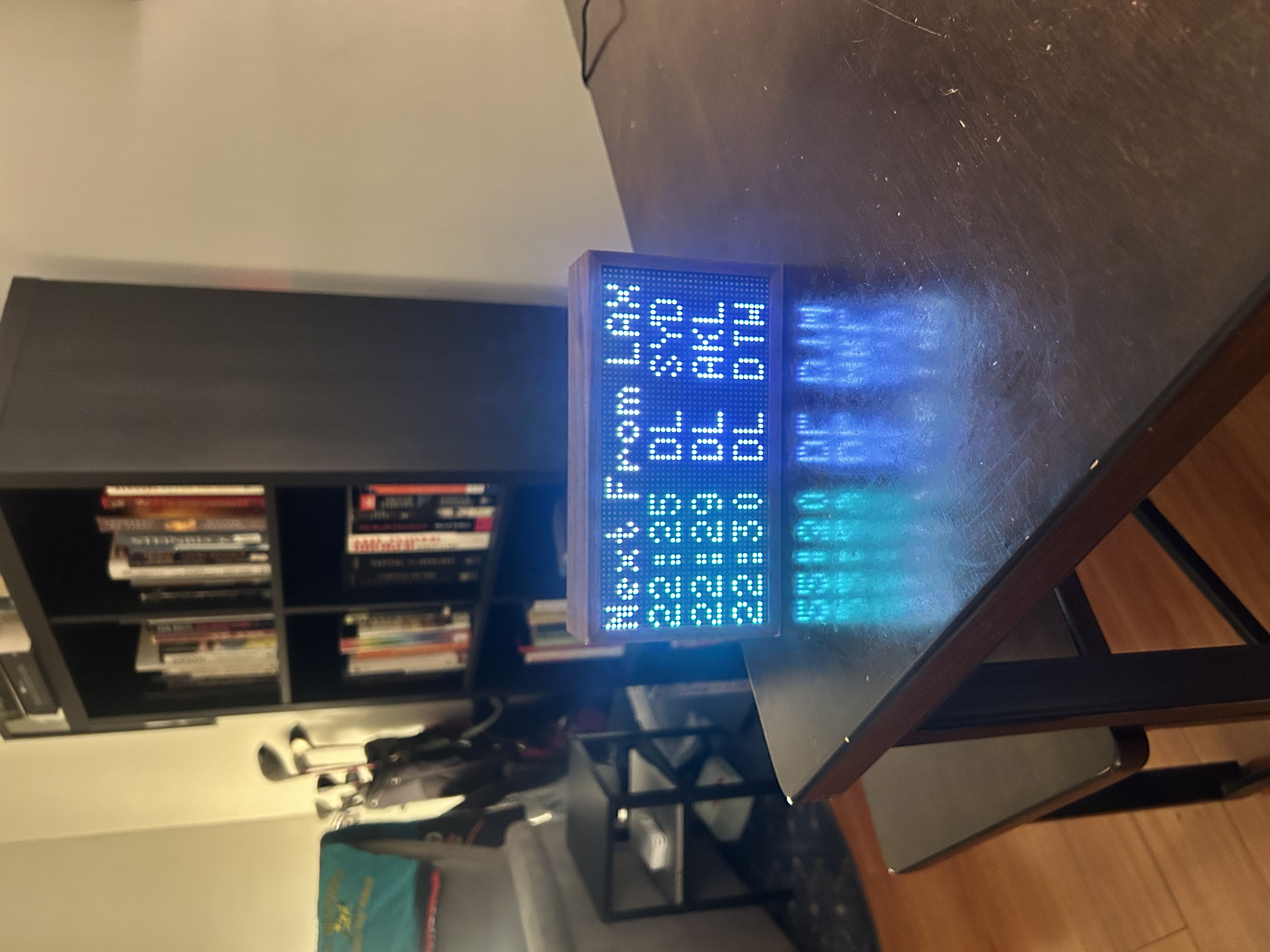 Tidbyt mounted by bookshelf